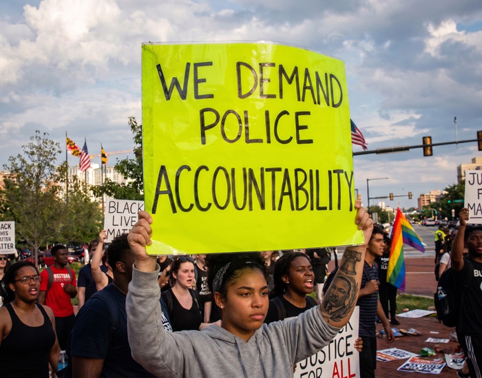 A protester is holding a sign that say "We demand police accountability"